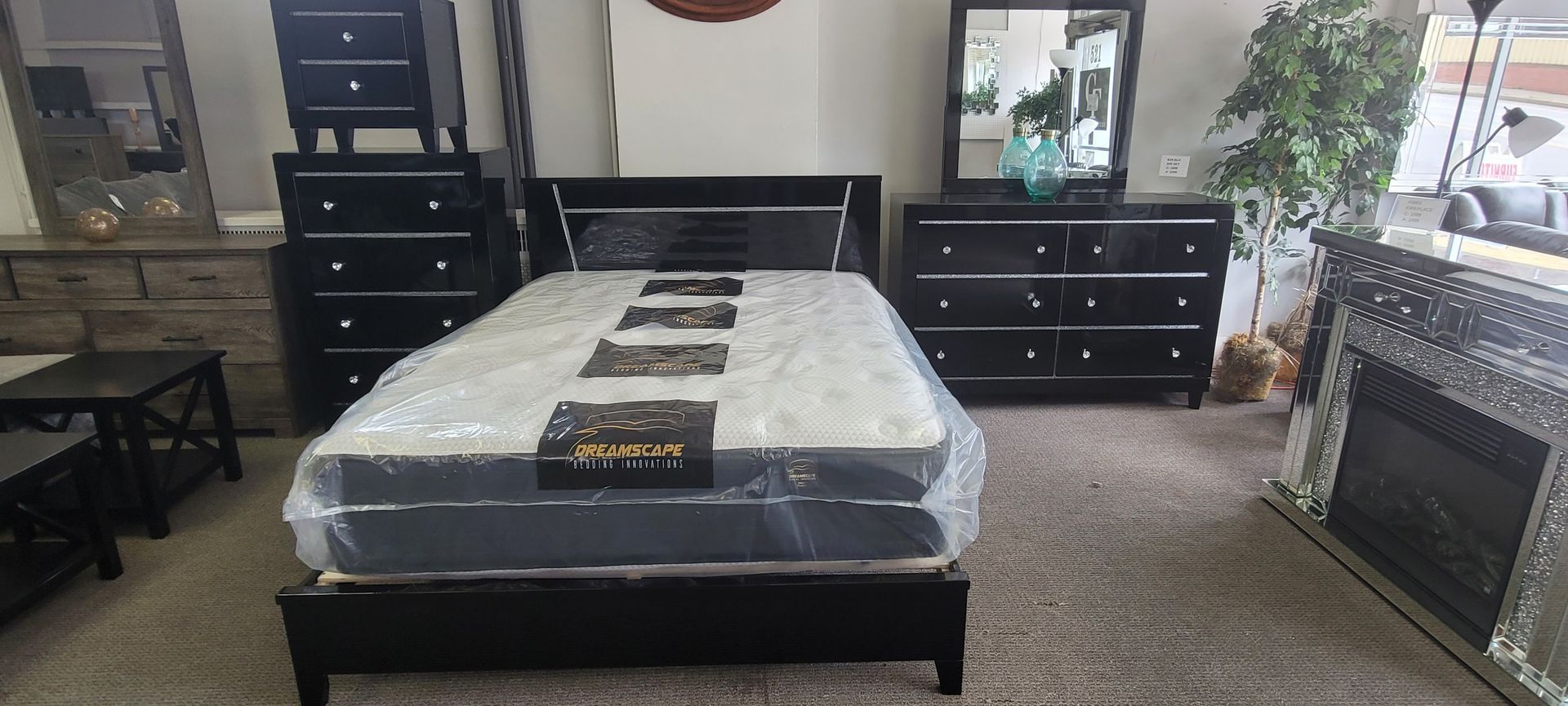 Bedroom furniture set with a bed, dresser, and chest. All in black, set on carpet.