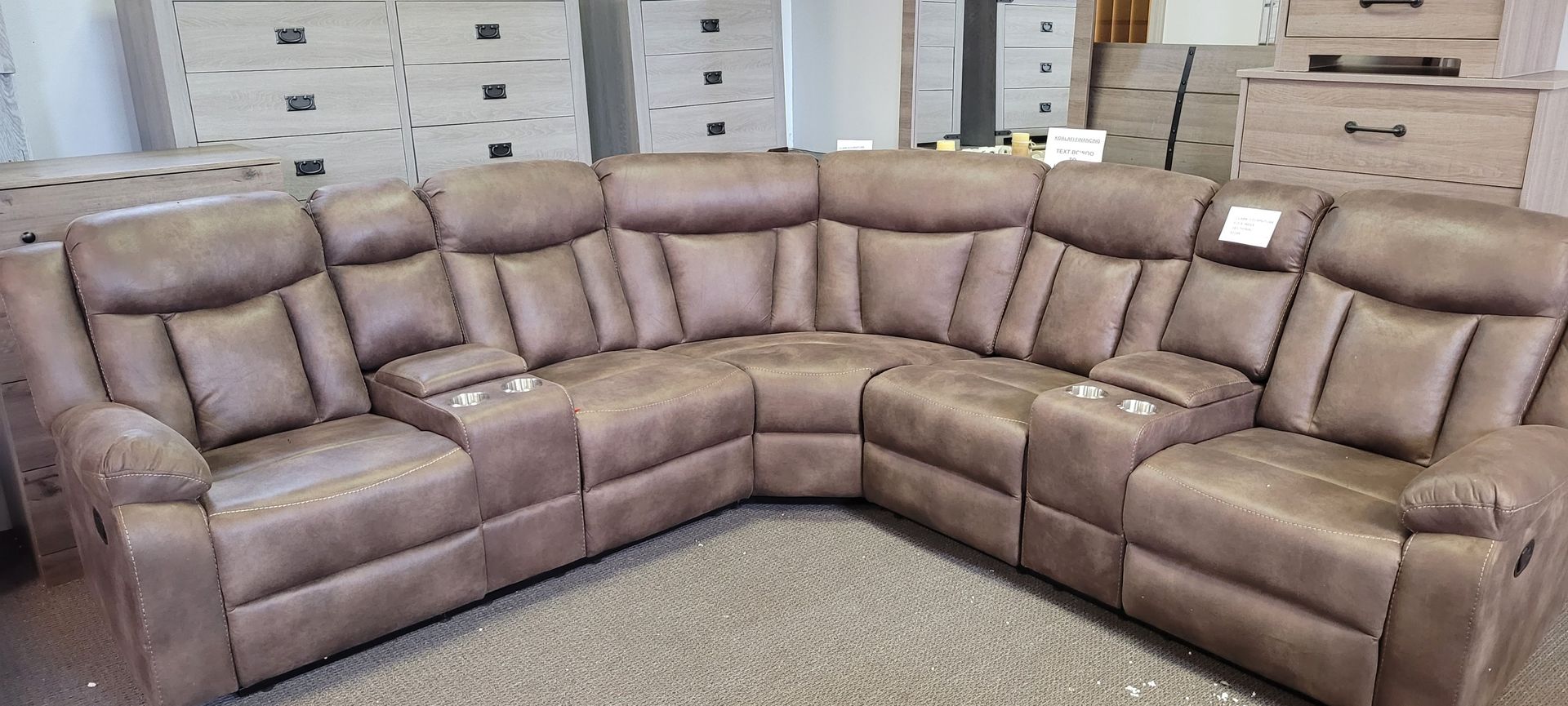 Brown sectional sofa with built-in cup holders in a showroom setting.