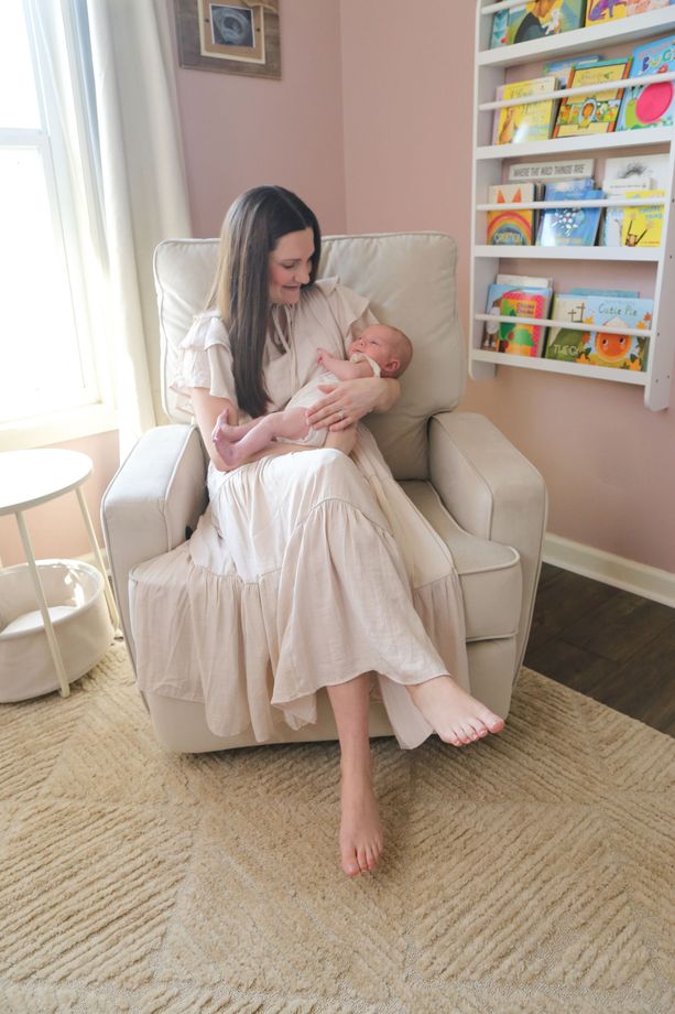 A woman is sitting in a chair holding a baby.