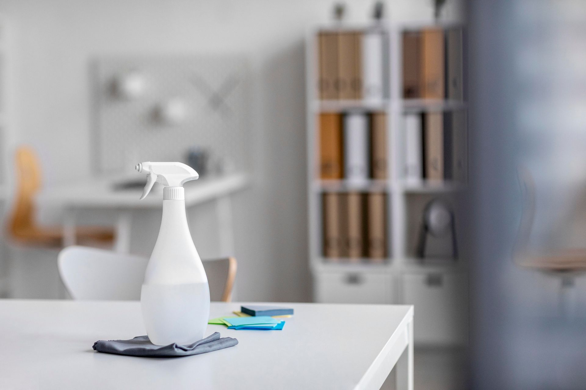 A spray bottle is sitting on a white table in an office.