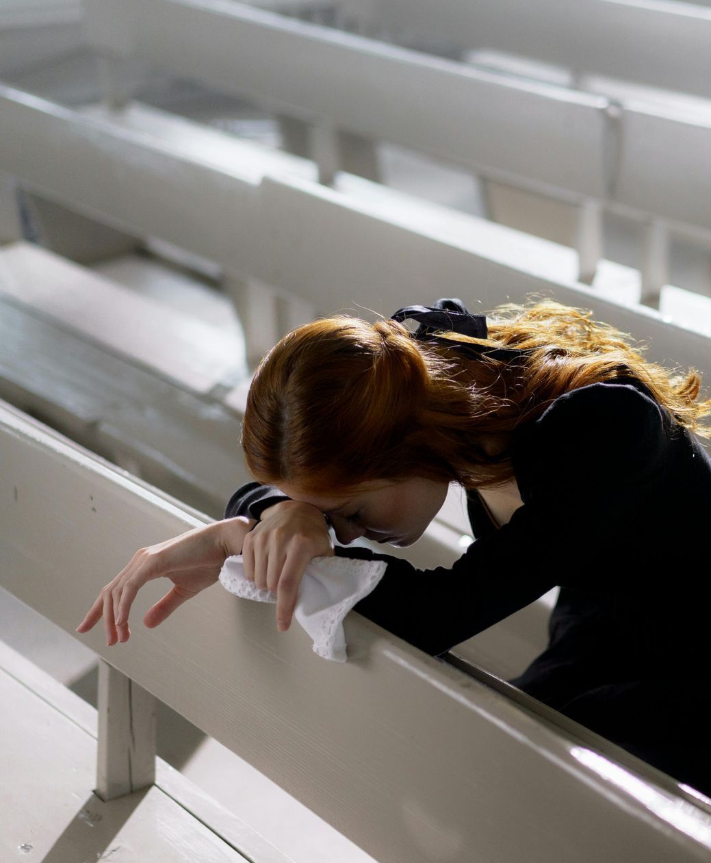 A woman sitting on a bench with her head on her hand