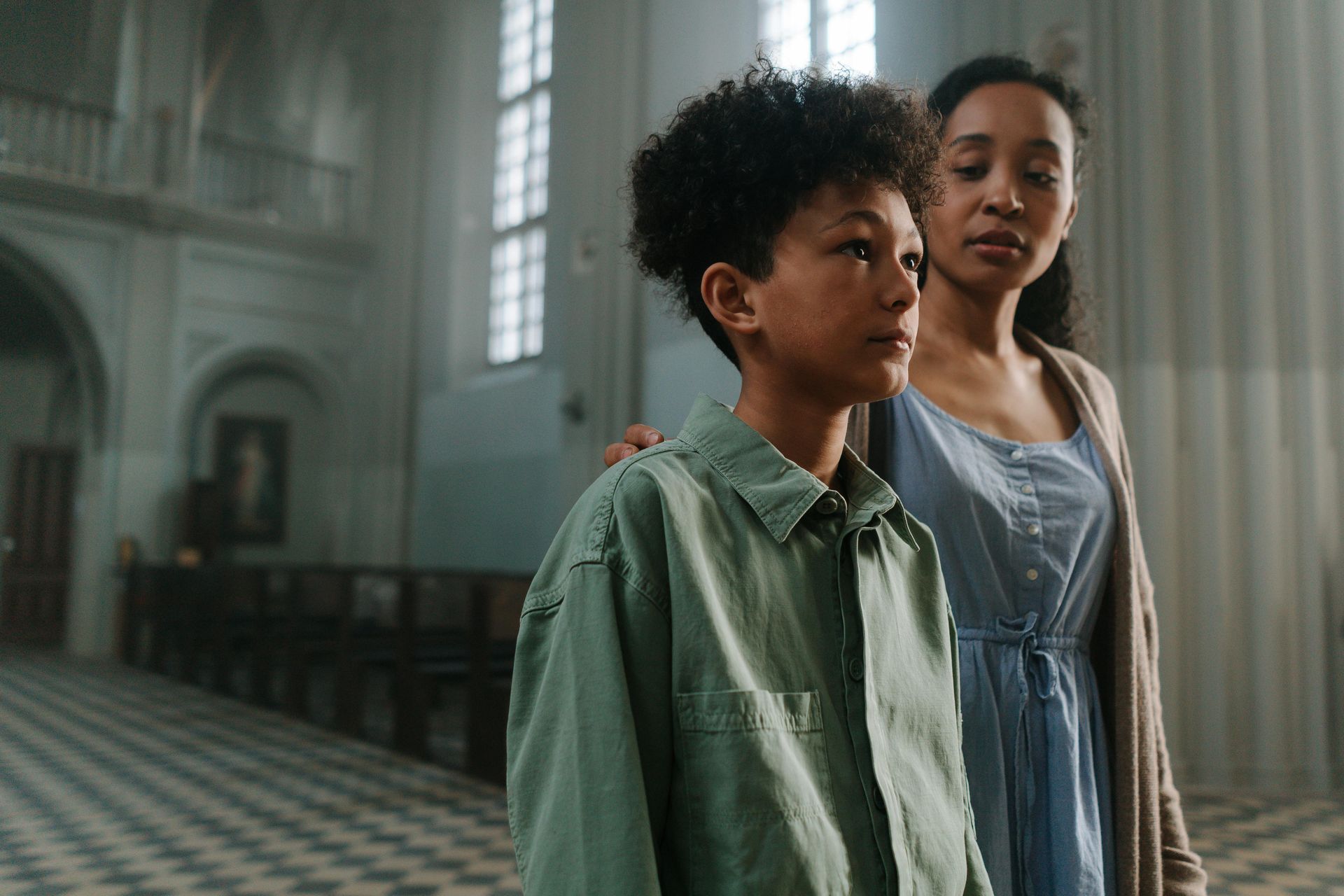 A woman and a boy are standing in a church.