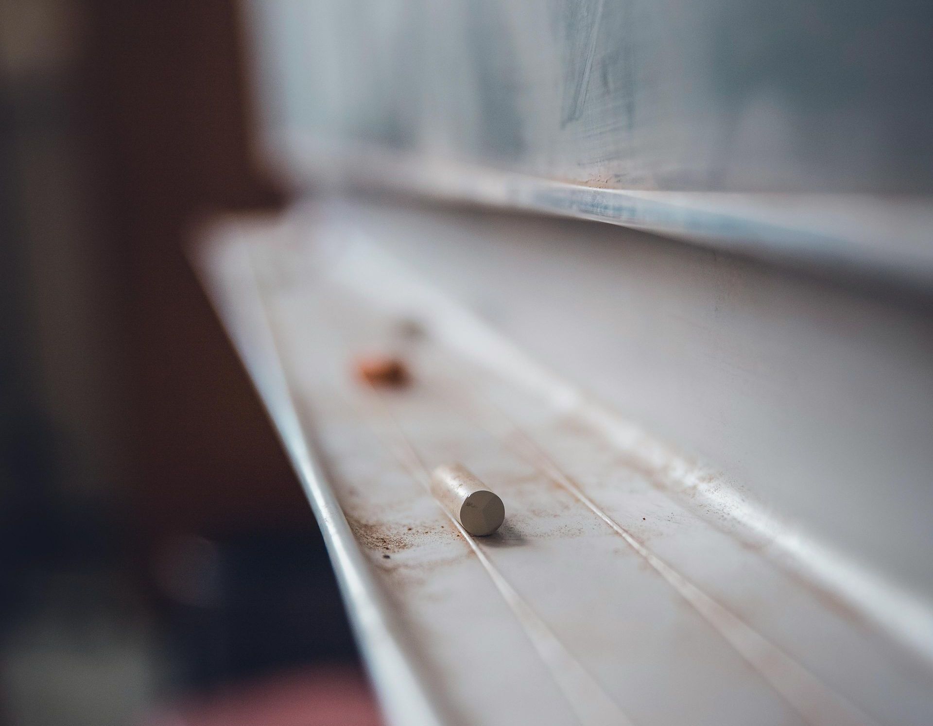 A close up of a chalkboard with a few pieces of chalk on it.