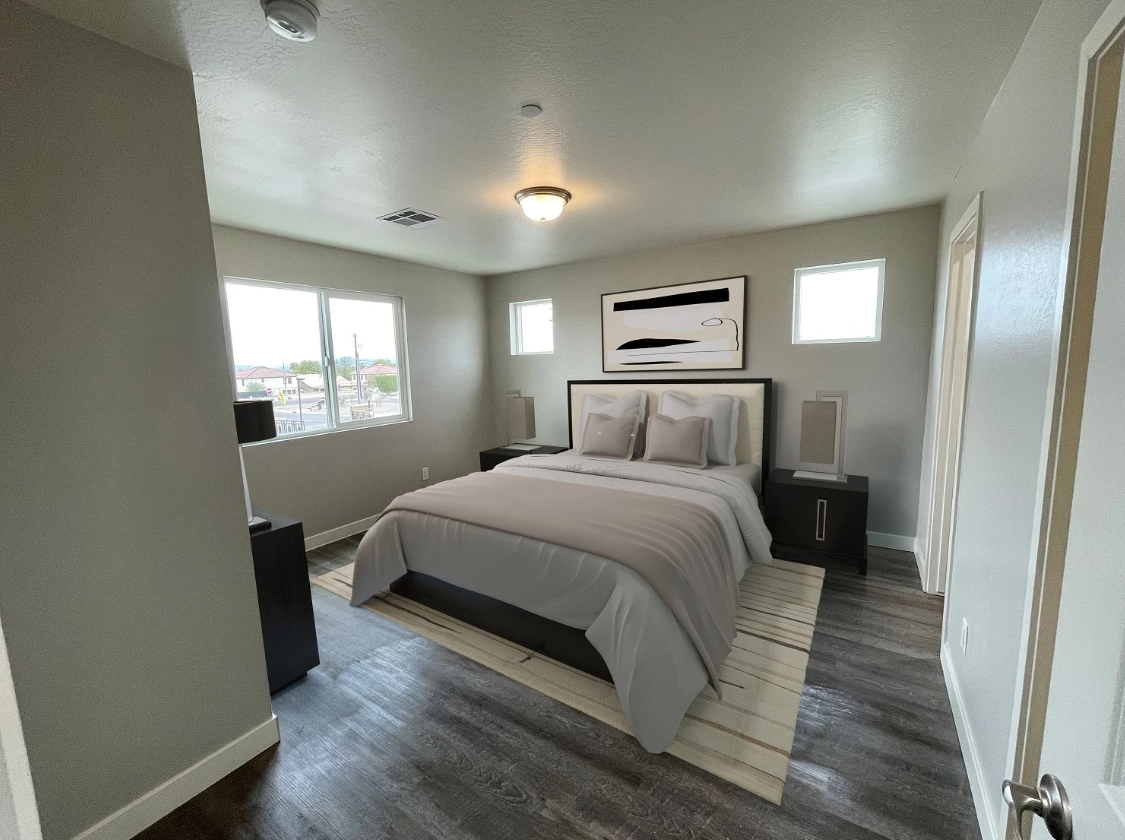 Bright bedroom with a made bed, gray flooring, two windows, and a ceiling light.