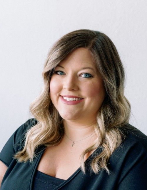 A woman in a black shirt is smiling for the camera.