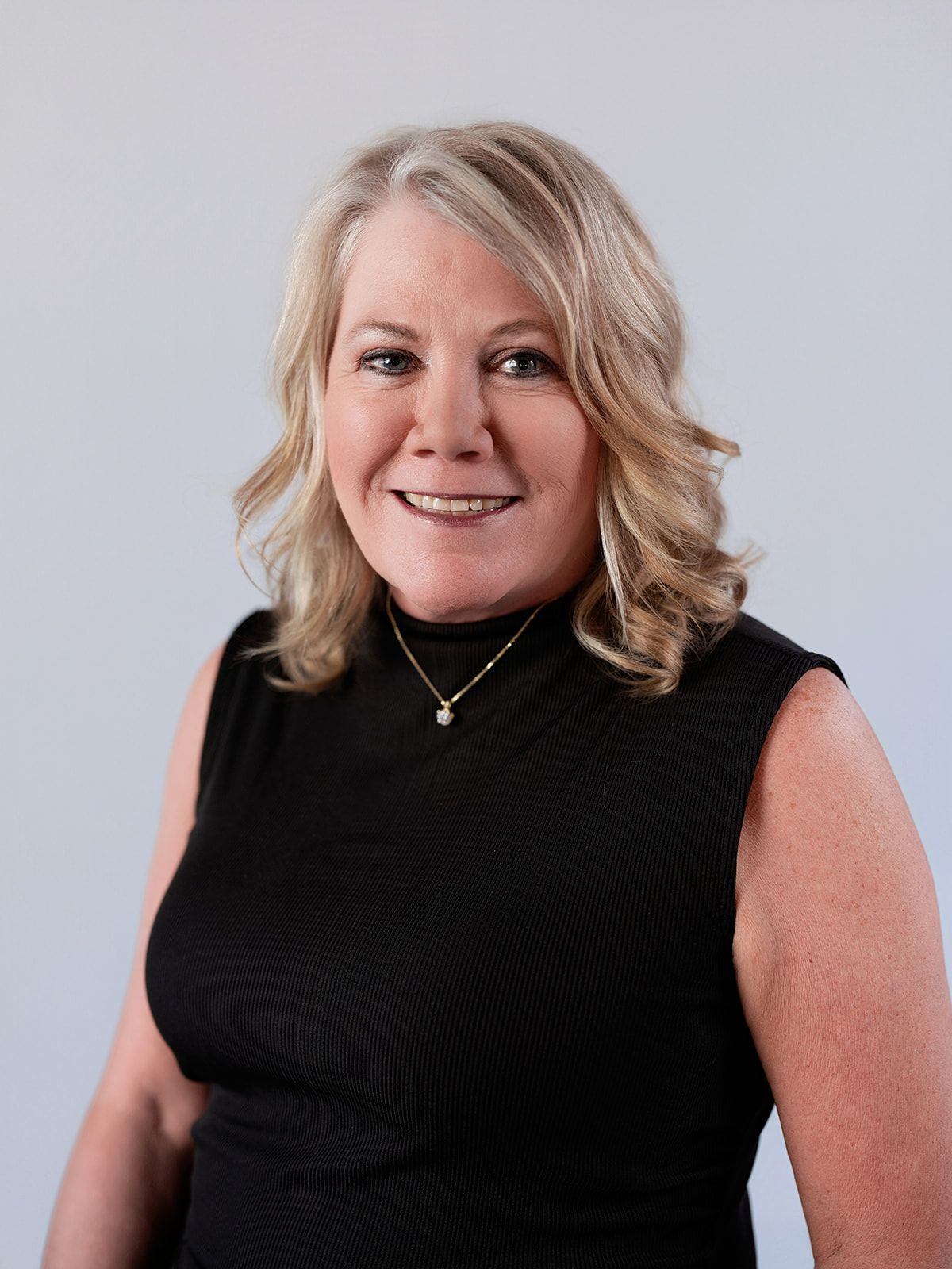 A woman in a blue and black dress is smiling for the camera.