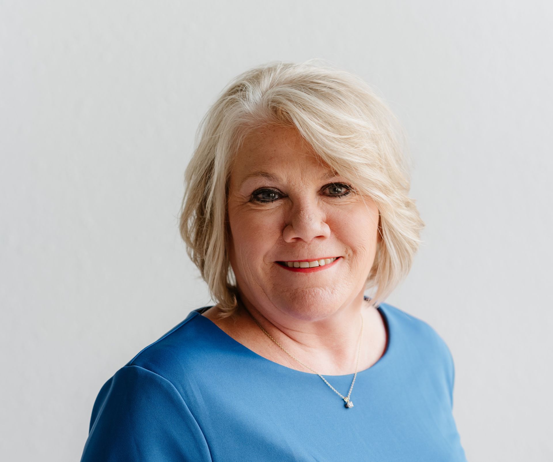 A woman in a blue and black dress is smiling for the camera.