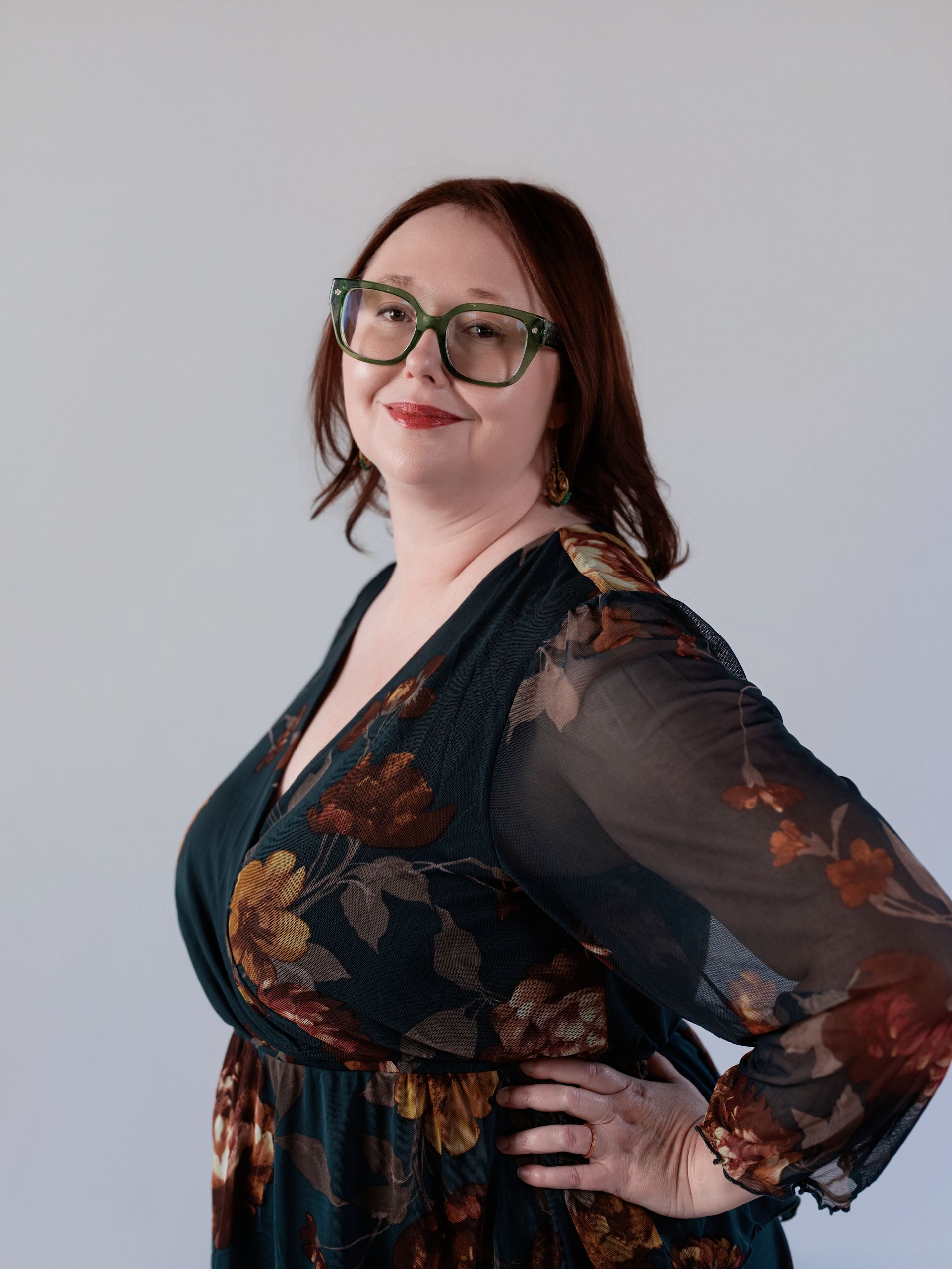 A woman in a blue dress and black jacket is smiling for the camera.