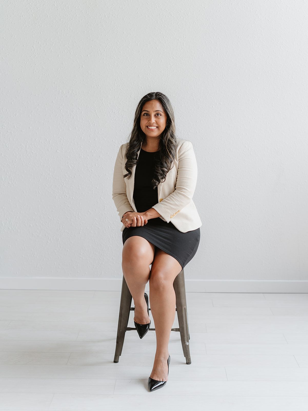 A woman with long black hair is wearing a pink shirt and a black jacket.