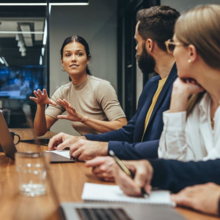 A group of people are sitting around a table having a meeting.