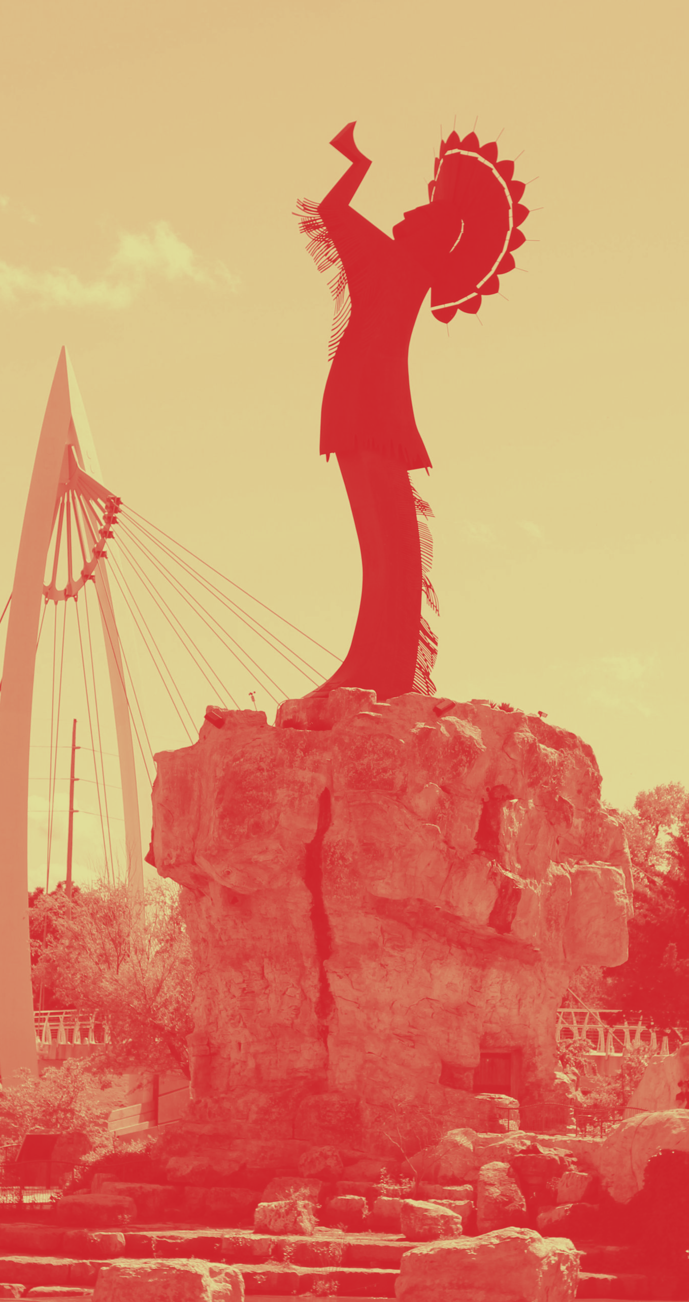 Keeper of the Plains statue in Wichita, Kansas, with a red overlay against a bridge and sky.
