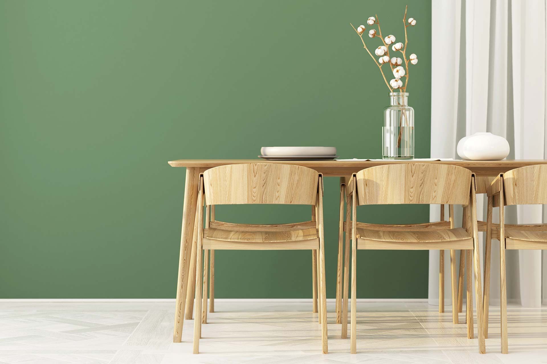 Minimalist dining room with wooden table and chairs against a green wall, white curtain, and vase centerpiece