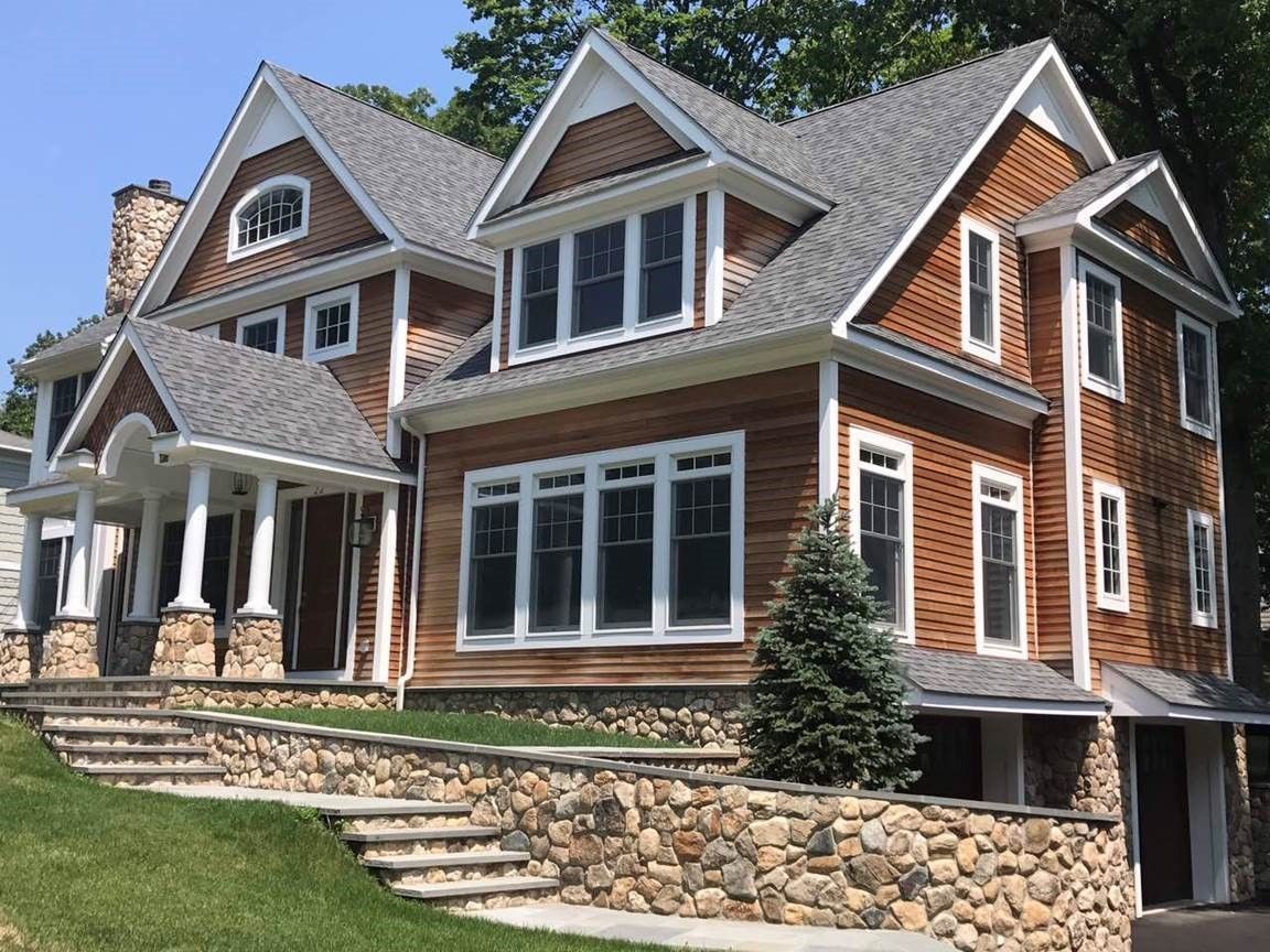 Large brick-and-stone suburban house with gabled roof, white trim, and front steps.