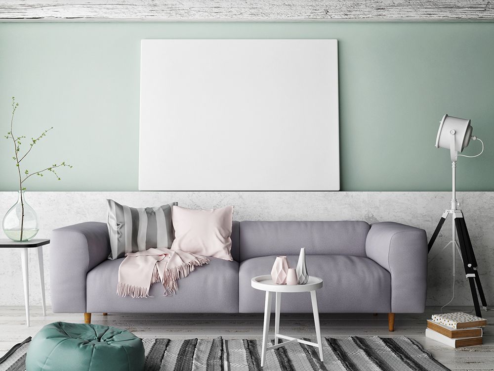 Modern living room with gray sofa, white table, floor lamp, and blank wall art on a mint wall