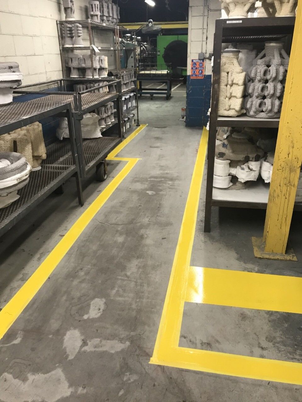 Industrial aisle with yellow floor markings and shelves of parts in a warehouse.