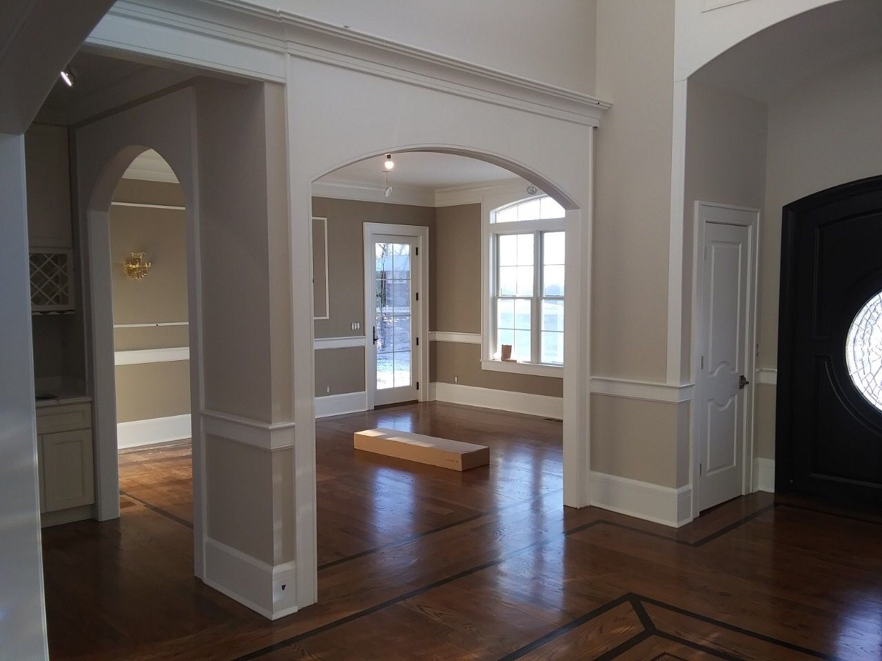 Empty room with hardwood floors, arched openings, and windows letting in natural light