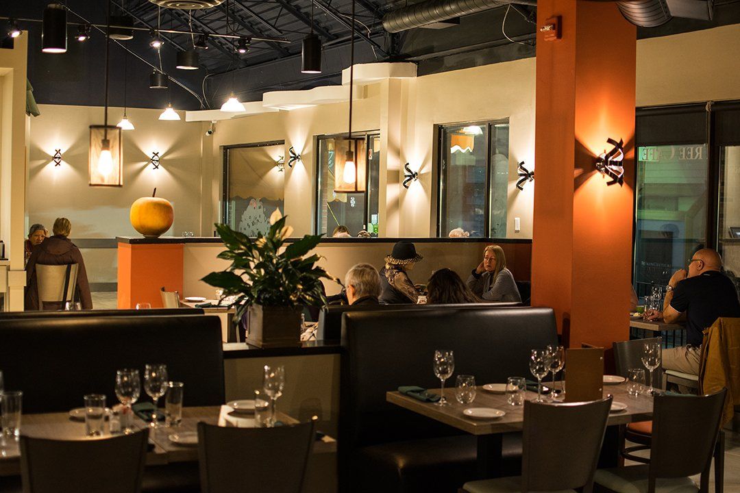 a restaurant with tables and chairs and people sitting at them .