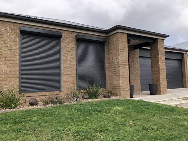 Brick House With Closed Roller Shutters