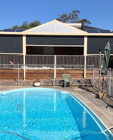 There Is a Large Swimming Pool in Front of A House — Phoenix Blinds In Albion Park Rail, NSW
