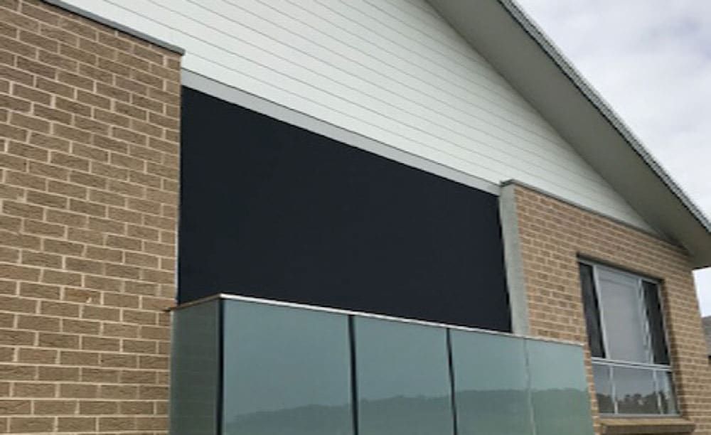 A Brick Building with A Black Awning on The Side of It — Phoenix Blinds In Albion Park Rail, NSW
