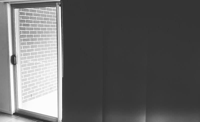 A Black and White Photo of A Sliding Glass Door Leading to A Brick Wall — Phoenix Blinds In Albion Park Rail, NSW
