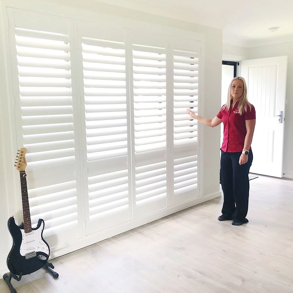 A Woman Is Standing in Front of A Window — Phoenix Blinds In Albion Park Rail, NSW
