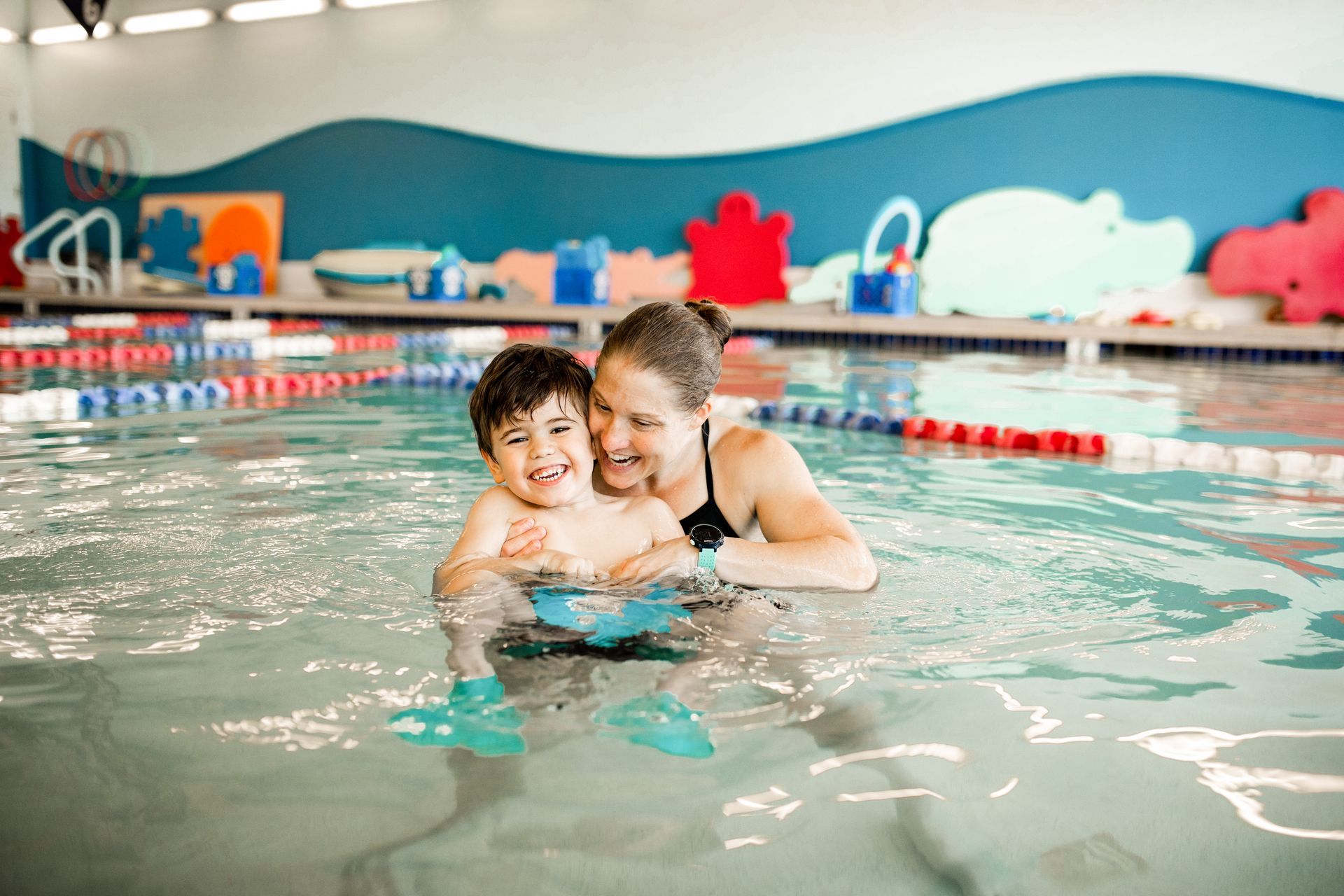 A woman is teaching a young boy how to swim in a swimming pool.