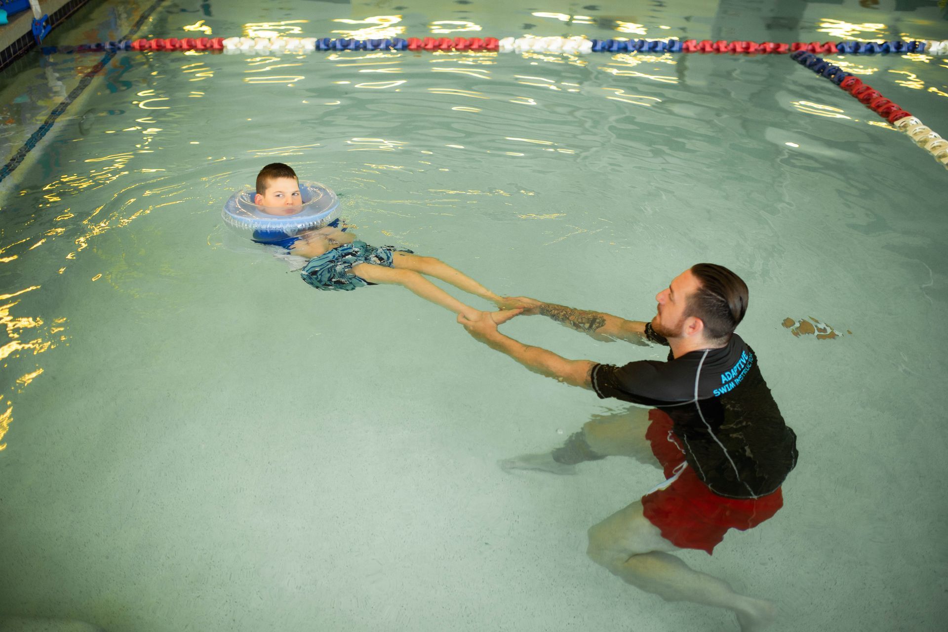 A man is teaching a child how to swim in a swimming pool.