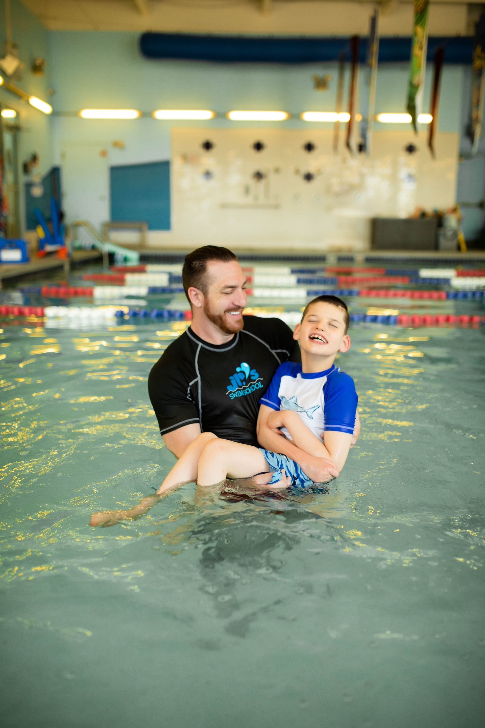 A man is holding a child in a swimming pool.