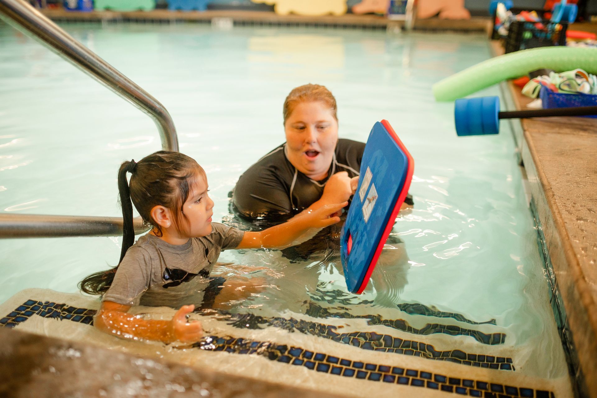 A young boy is swimming in a swimming pool.