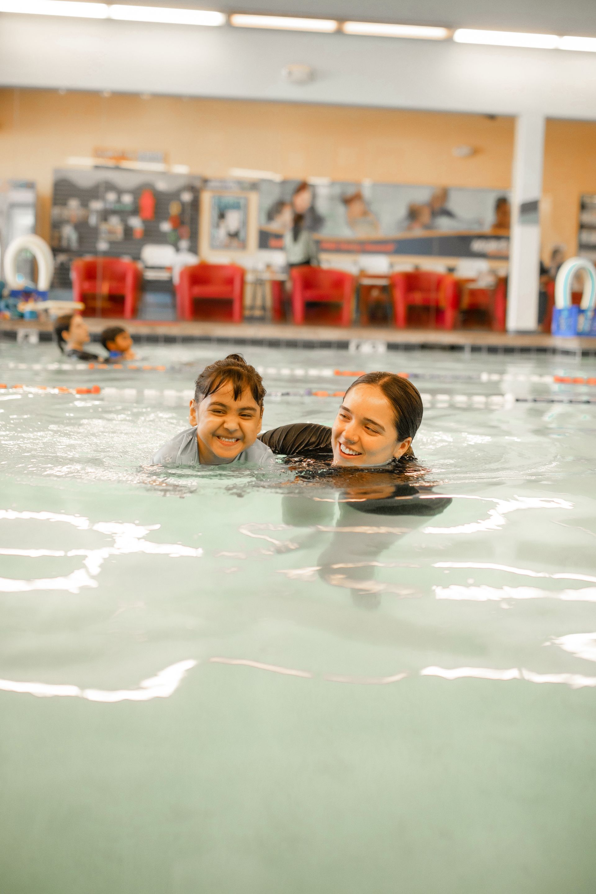A woman is teaching a boy how to swim in a swimming pool.