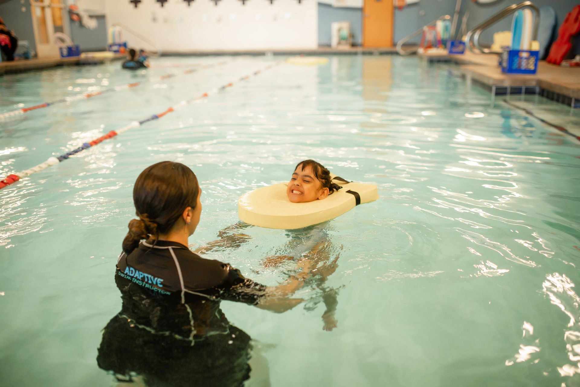 A woman is teaching a child how to swim in a swimming pool.