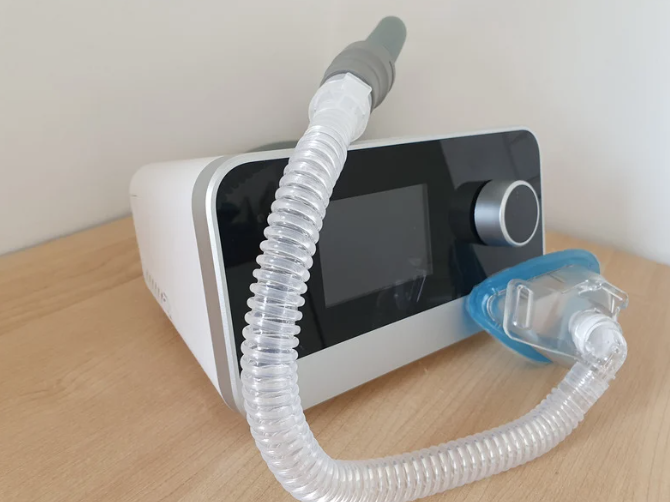A machine with a hose attached to it is sitting on a wooden table.