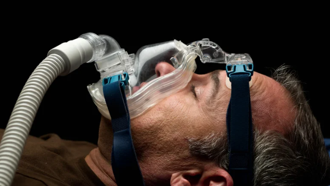 A man is wearing a cpap mask on his face.