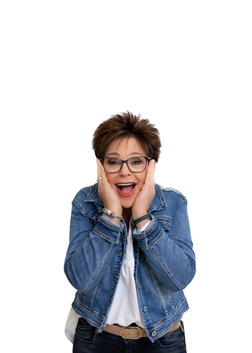Person in a blue denim jacket and glasses, smiling with hands on cheeks against a white background