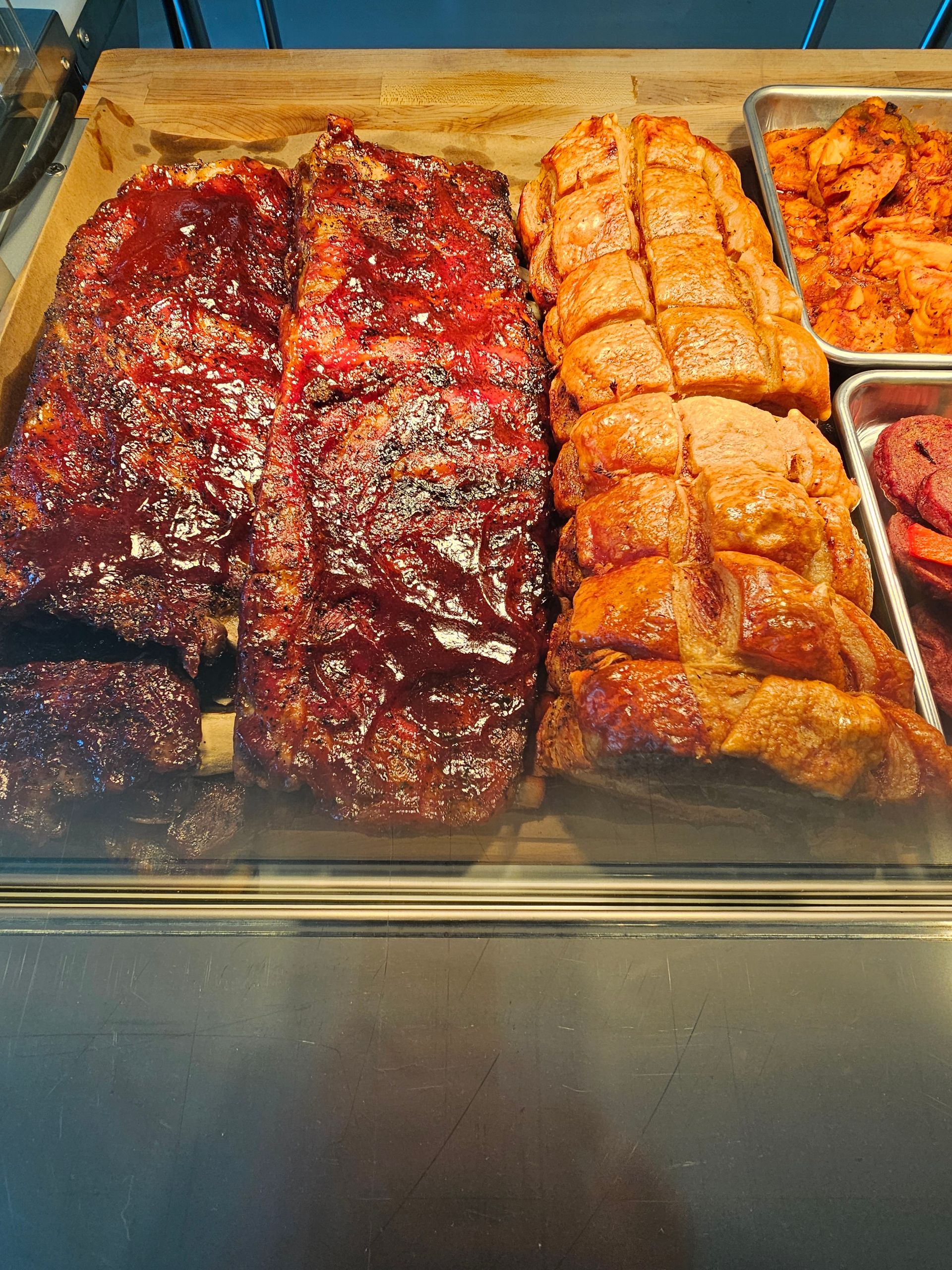 A variety of meats are displayed in a glass case.