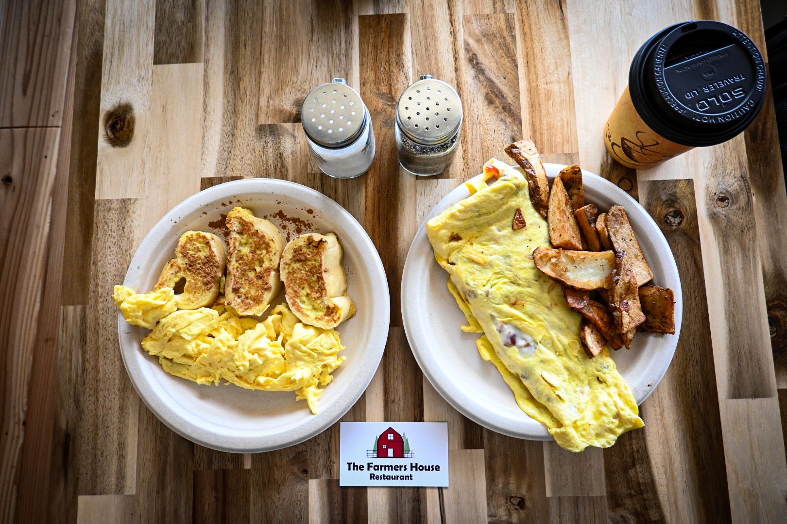 A wooden table topped with two plates of food and a cup of coffee.