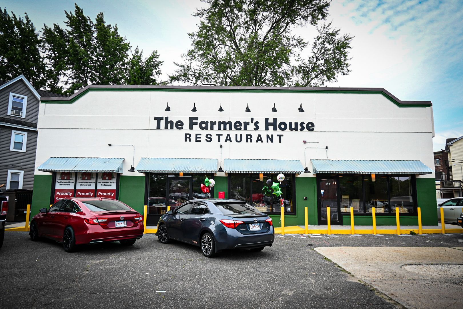 Two cars are parked in front of the farmer 's house restaurant