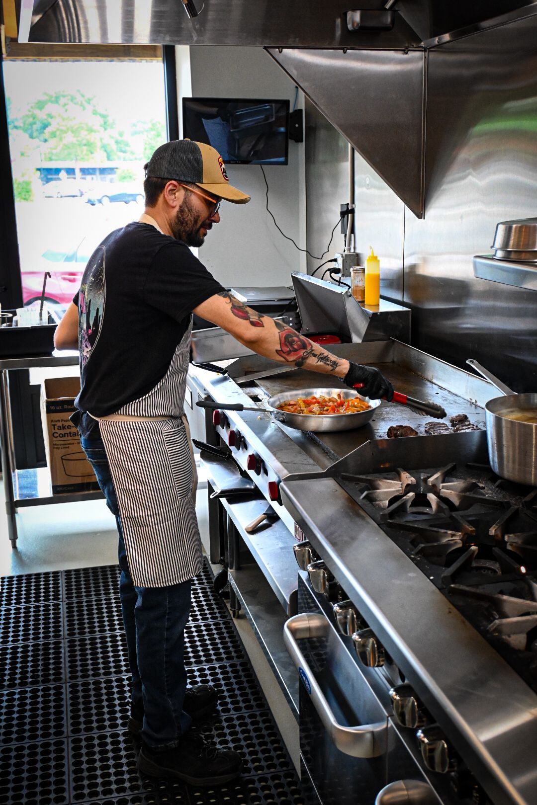A man is cooking food on a stove in a kitchen.