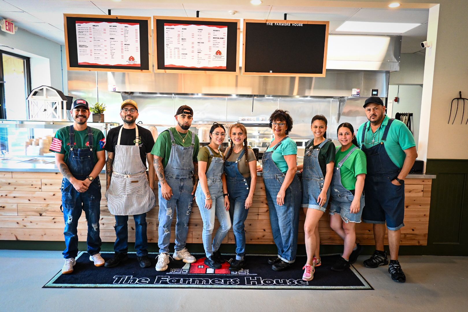 A group of people in overalls are posing for a picture in a restaurant.
