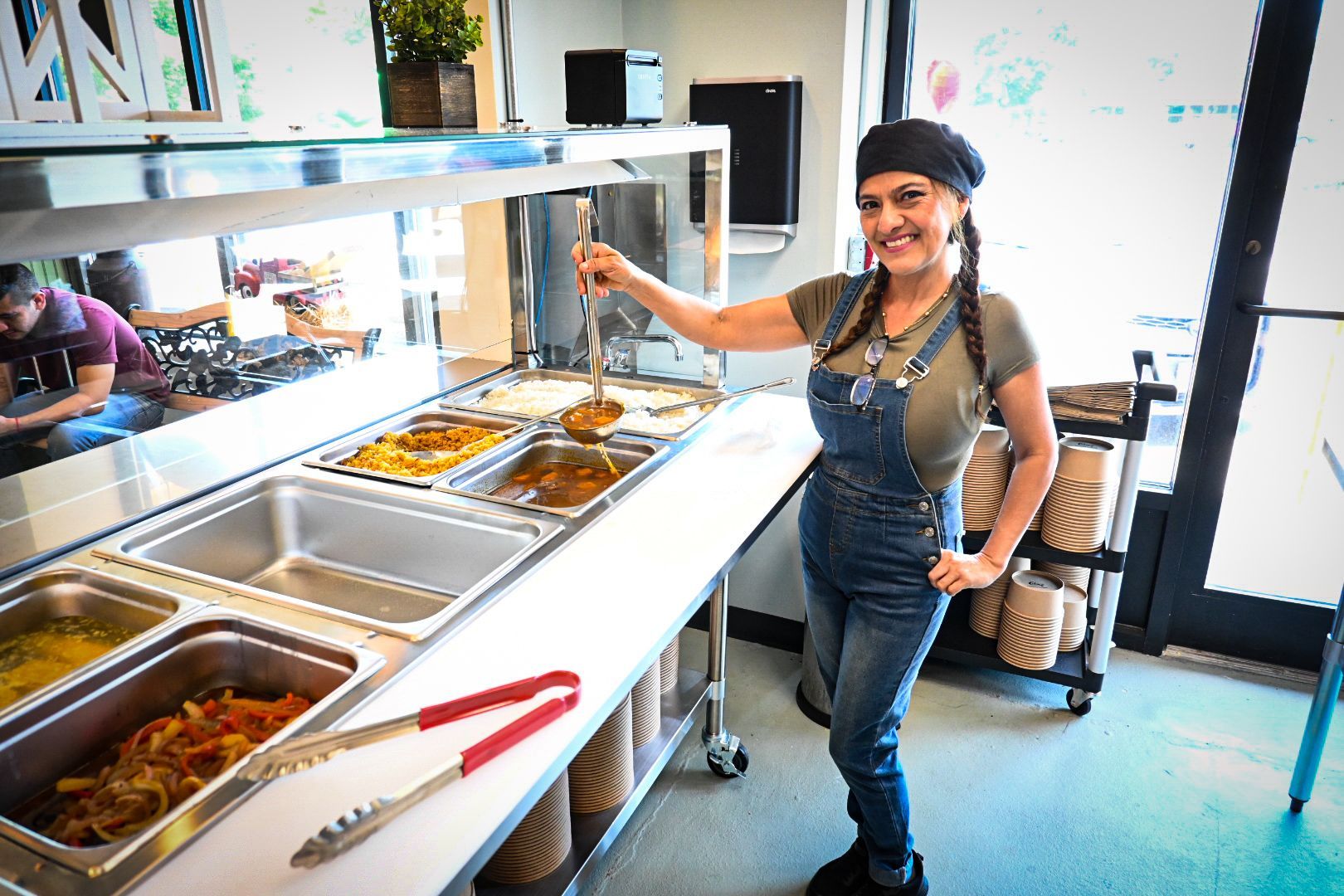 A woman is standing in front of a buffet line in a restaurant.