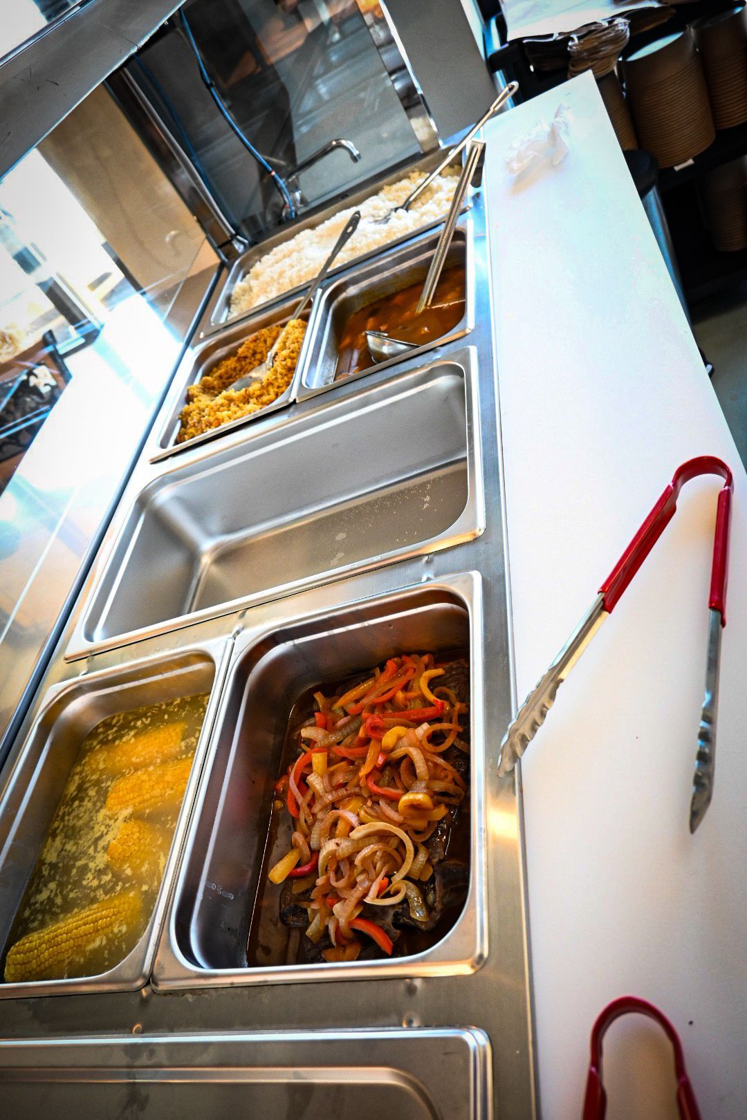 A buffet line filled with lots of food and tongs.