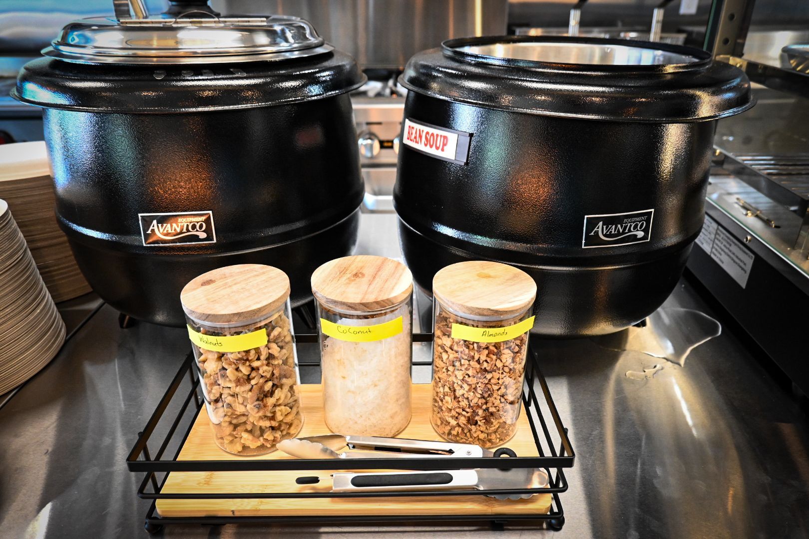 Two pots of soup are sitting on a counter next to jars of granola.