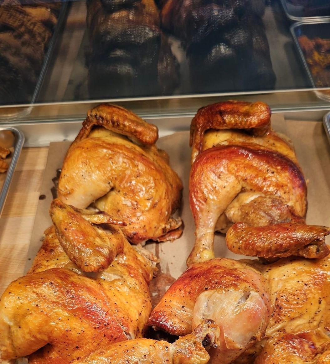Two roasted chickens are sitting on a table in a display case.