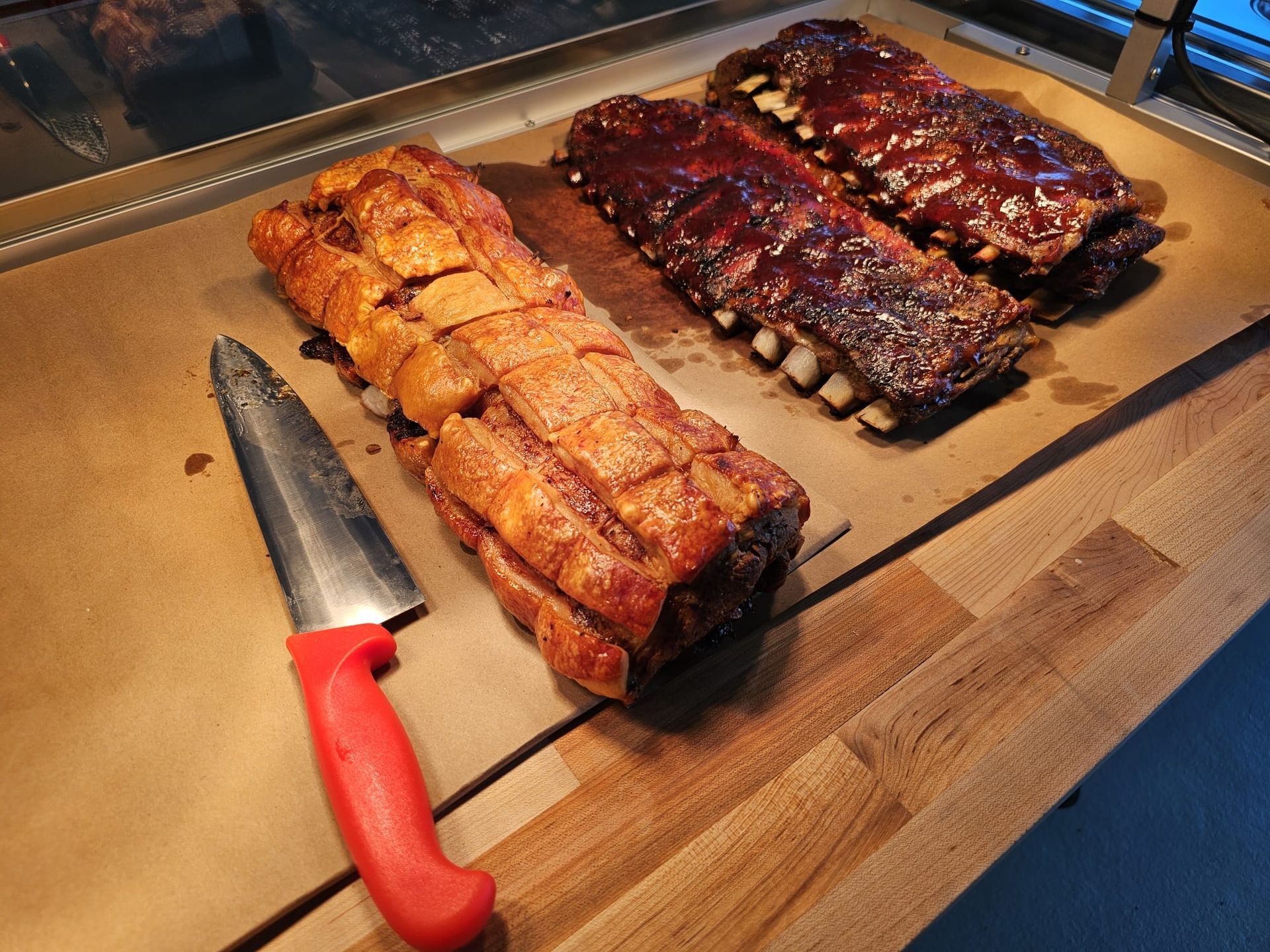 Sliced fried and glazed ham with red knife.