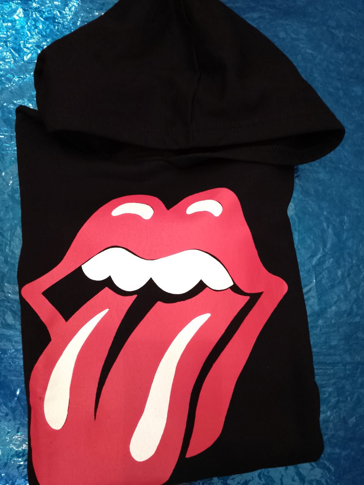 Sudadera negra con el logotipo de los Rolling Stones (lengua y labios rojos) sobre fondo azul.