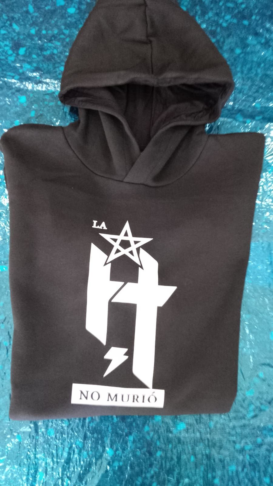 Sudadera negra con capucha, con un gráfico blanco y las palabras “NO MURIO” sobre un fondo azul texturizado.