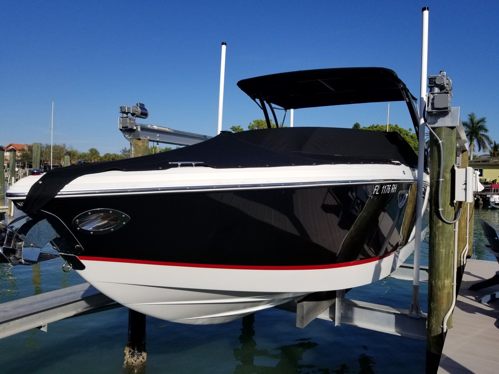 Black and white boat is sitting on a lift in the water on our annual Maintenace program.