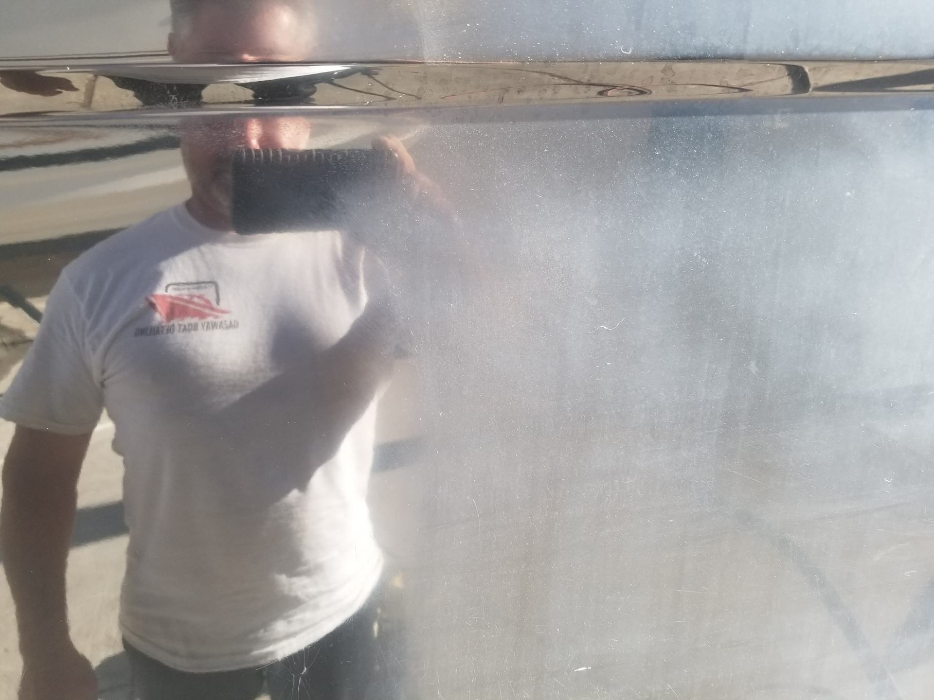 Standing in front of a boat showing the difference in oxidation removal.