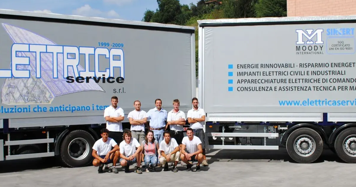 Team di Elettrica Service davanti ai camion aziendali, simbolo della crescita dell’azienda nel settore elettrico e fotovoltaico